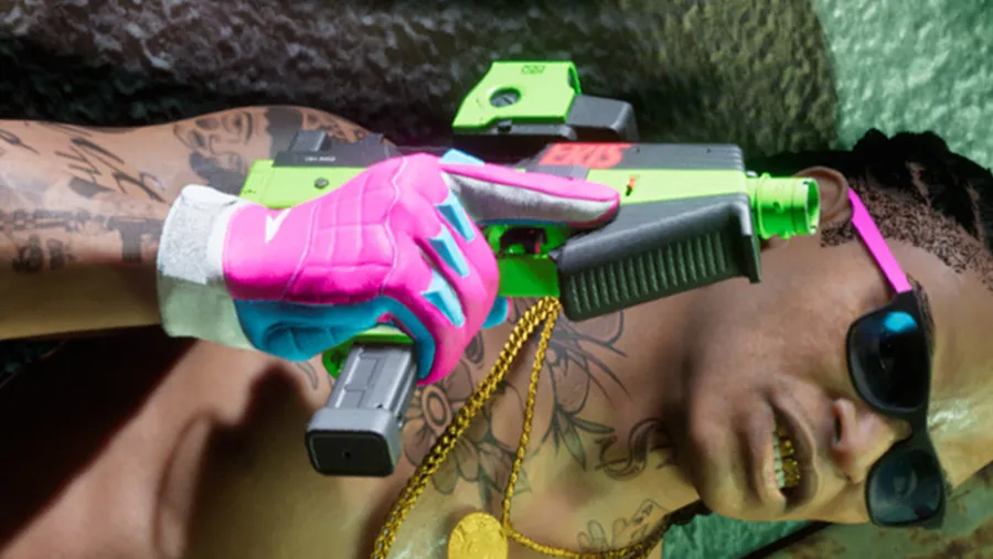 Overhead close-up of a tattooed man in sunglasses holding a bright green and pink compact submachine gun, from an official GTA 6 screenshot