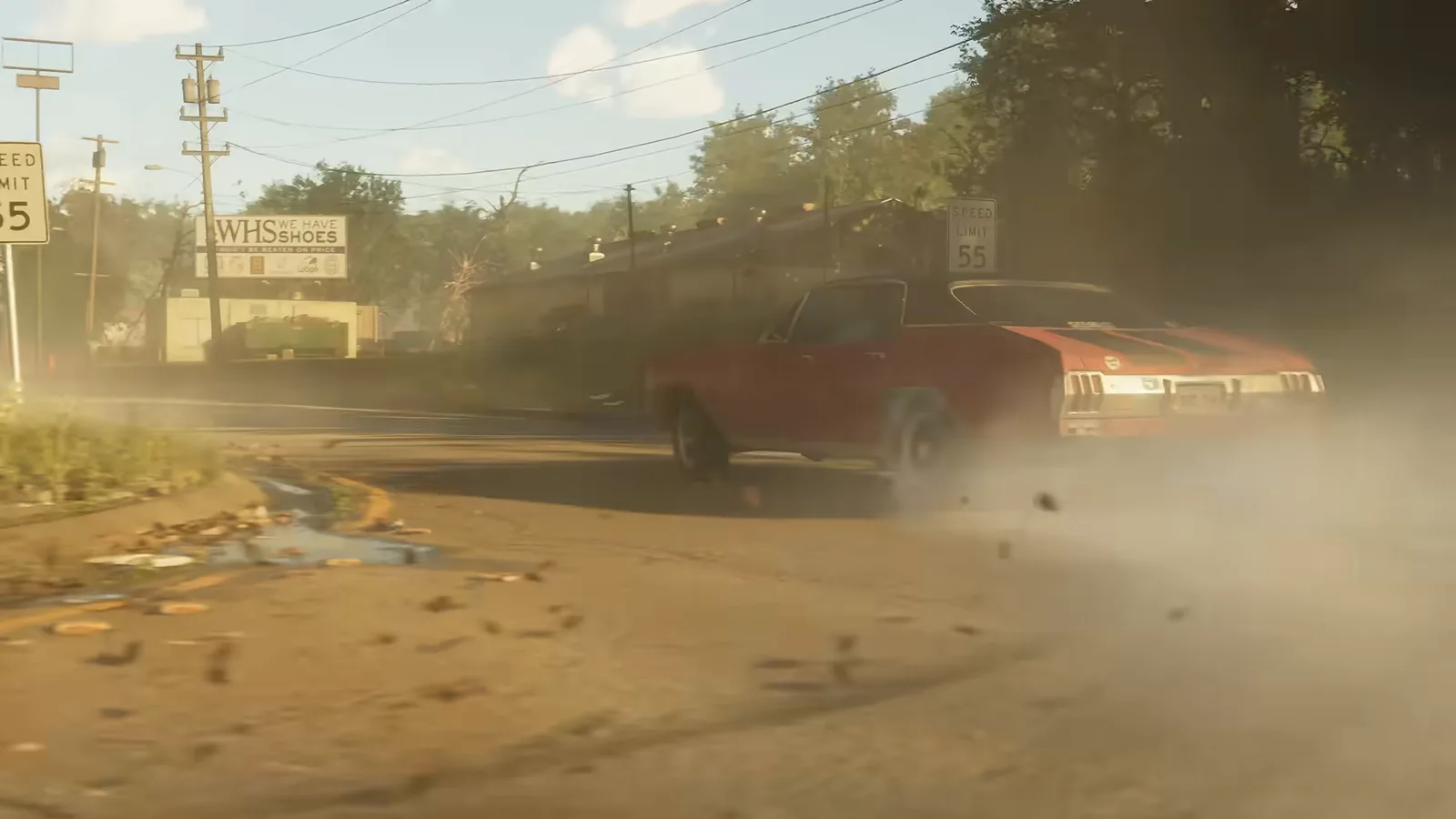 A red muscle car kicking up dust as it drifts out of a roadside store's lot, from Trailer 1.