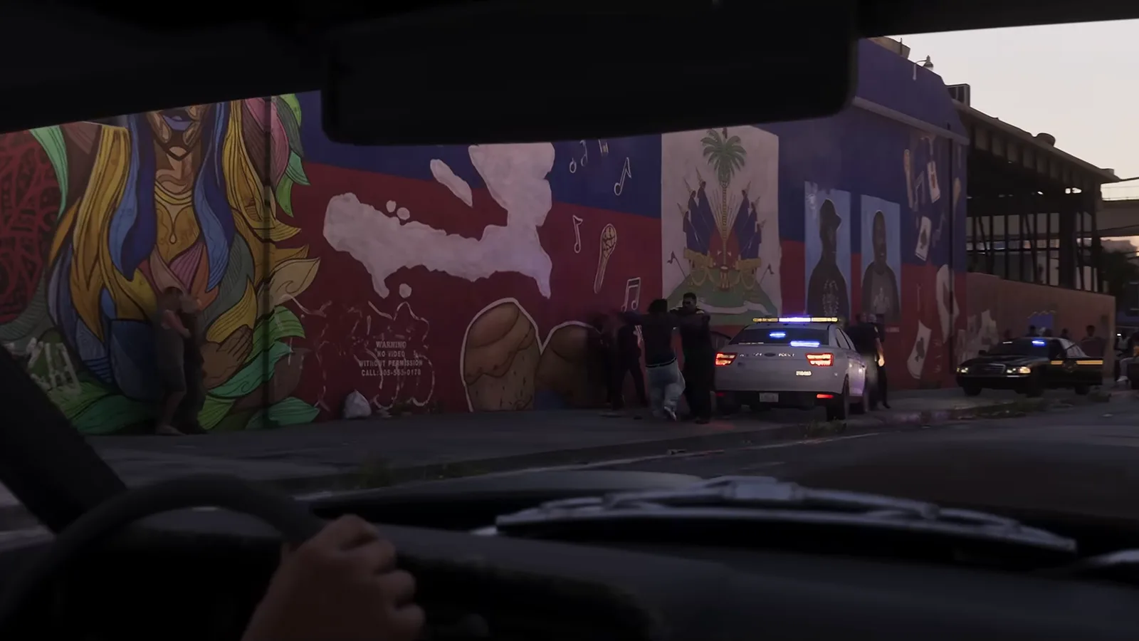 A driver's view of police cars and officers stopped ahead on a Vice City street, from Trailer 2.